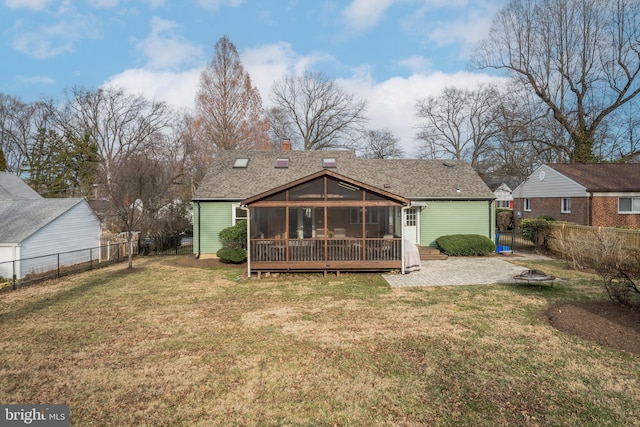 rear view of property featuring a yard, a chimney, a fenced backyard, and a sunroom