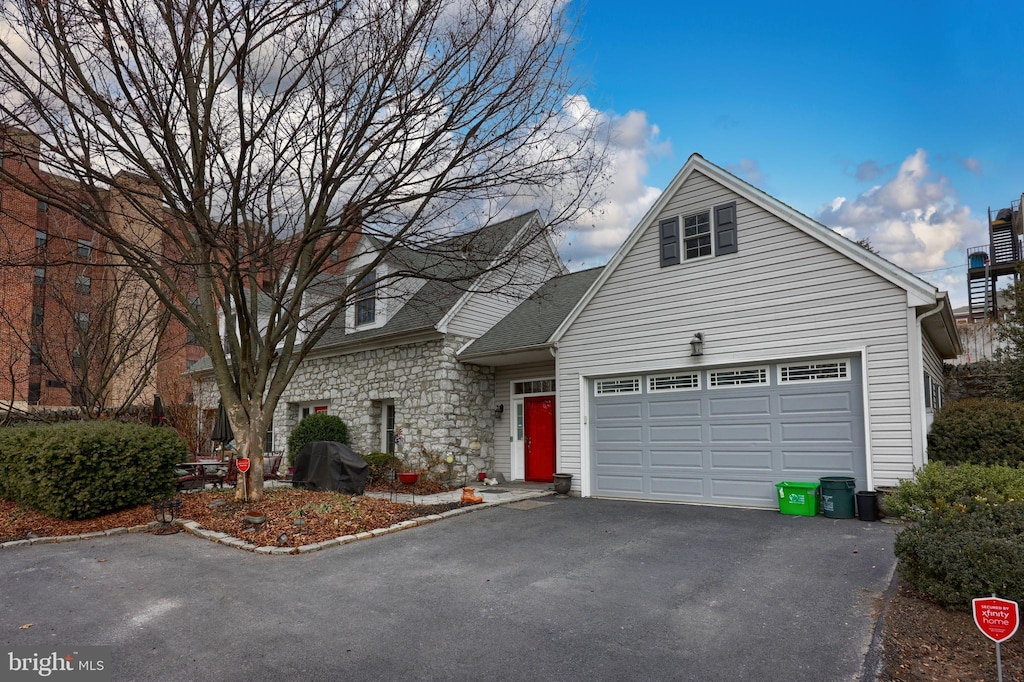 view of front of home featuring aphalt driveway, stone siding, and a garage