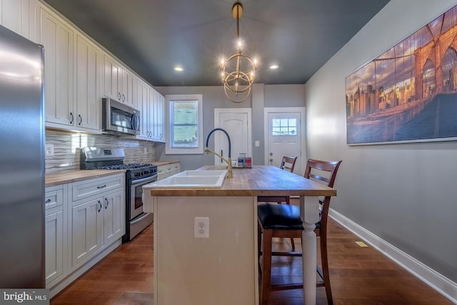 kitchen featuring wood counters, baseboards, white cabinets, appliances with stainless steel finishes, and decorative backsplash