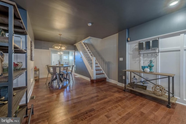 dining area featuring wood finished floors, visible vents, baseboards, stairs, and an inviting chandelier