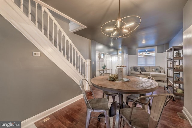 dining area featuring a notable chandelier, stairway, baseboards, and wood finished floors