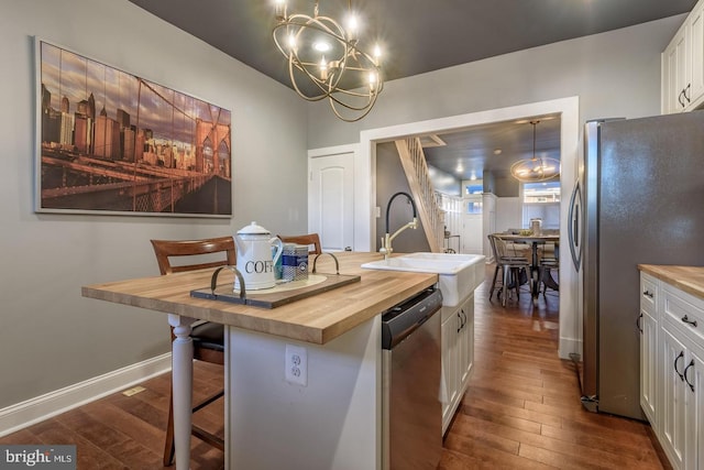 kitchen featuring stainless steel appliances, white cabinetry, wood counters, and dark wood-type flooring