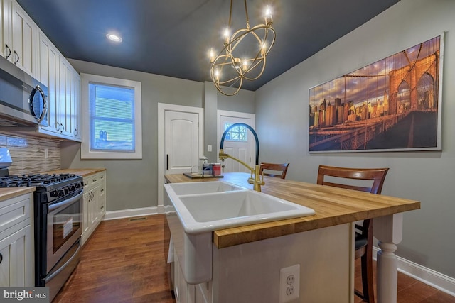 kitchen featuring stainless steel appliances, butcher block counters, backsplash, and white cabinetry