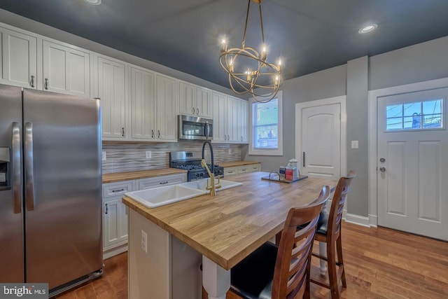 kitchen with a notable chandelier, stainless steel appliances, dark wood-style flooring, wooden counters, and decorative backsplash