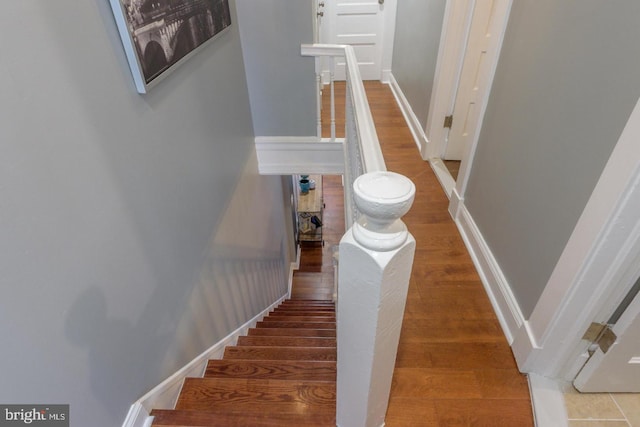 staircase with baseboards and wood finished floors