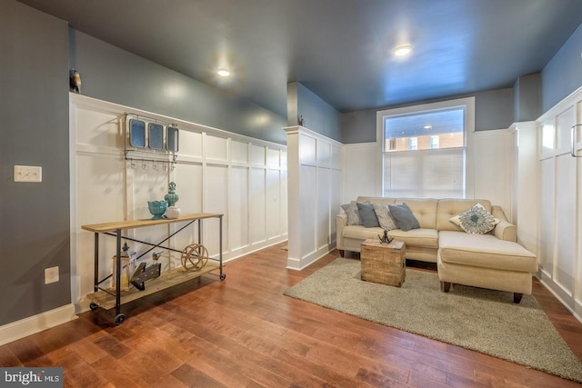 living area with a wainscoted wall, wood finished floors, and a decorative wall