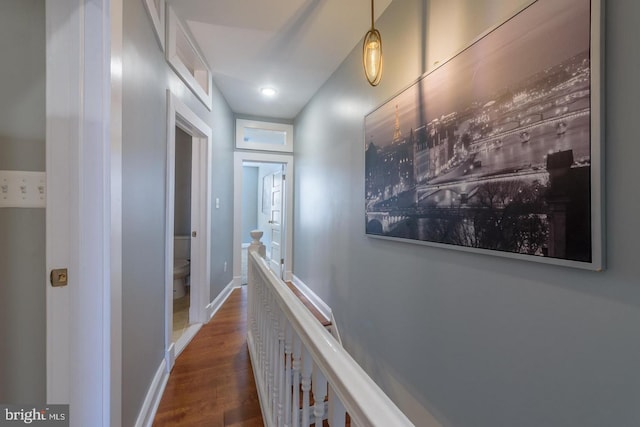 hallway with dark wood-style flooring, an upstairs landing, and baseboards