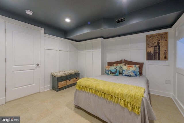 bedroom featuring baseboards, a decorative wall, visible vents, and recessed lighting