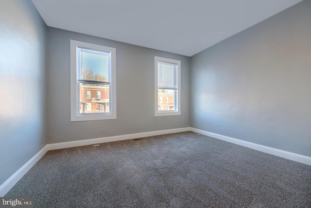 carpeted spare room featuring baseboards and vaulted ceiling