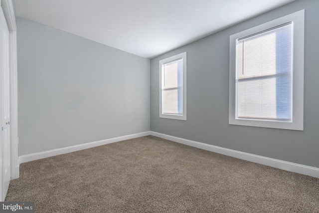 empty room featuring baseboards and carpet flooring