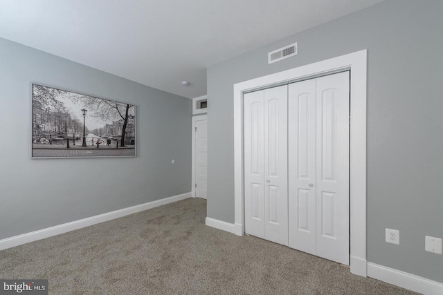 unfurnished bedroom with a closet, carpet, visible vents, and baseboards