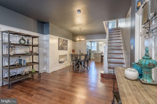 dining room featuring a chandelier, dark wood-style flooring, stairway, and baseboards