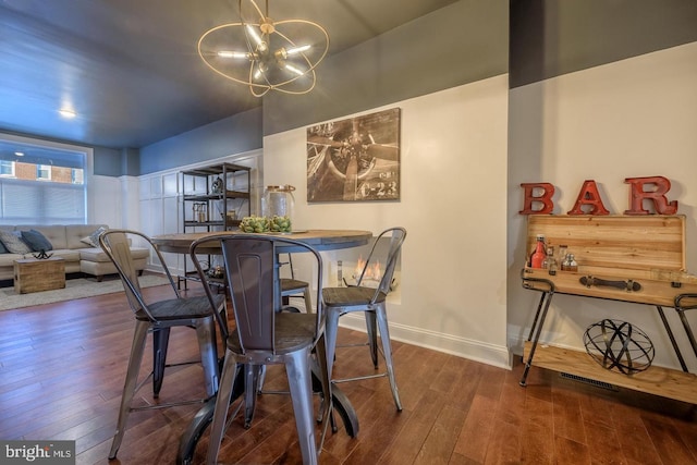 dining room featuring wood-type flooring, baseboards, and an inviting chandelier