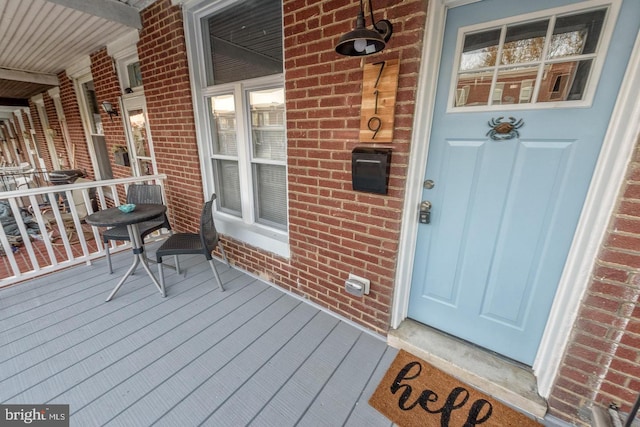 property entrance with covered porch and brick siding