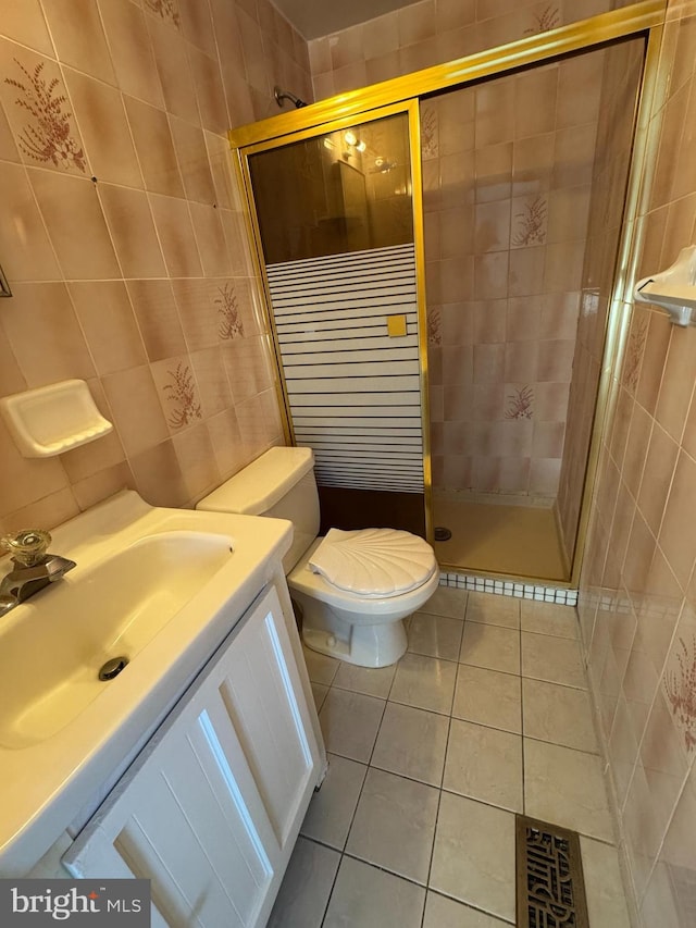 bathroom featuring toilet, a stall shower, tile patterned flooring, and tile walls
