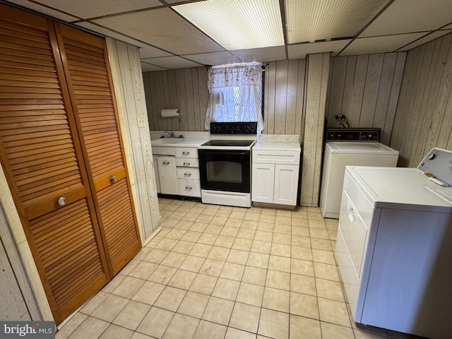 kitchen with a drop ceiling, black electric range oven, light countertops, washing machine and dryer, and a sink