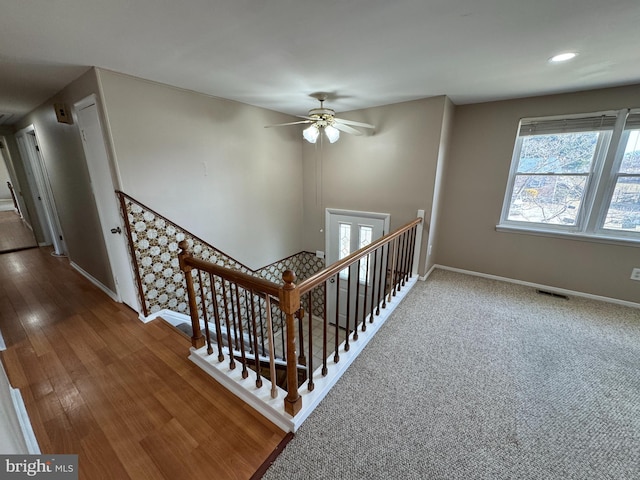 stairs featuring a ceiling fan, visible vents, baseboards, and wood finished floors