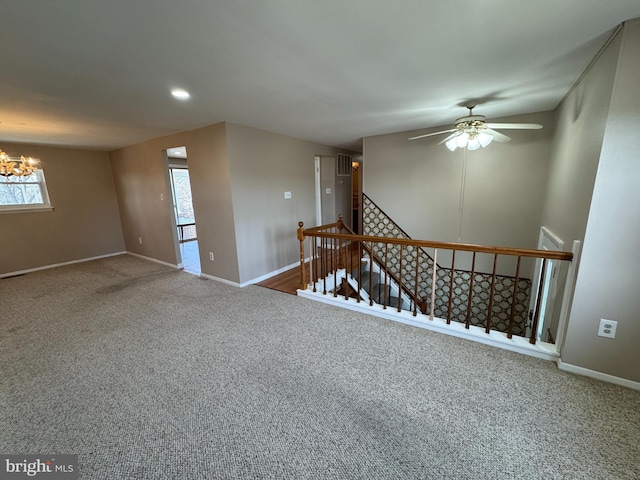 carpeted empty room with baseboards and ceiling fan with notable chandelier