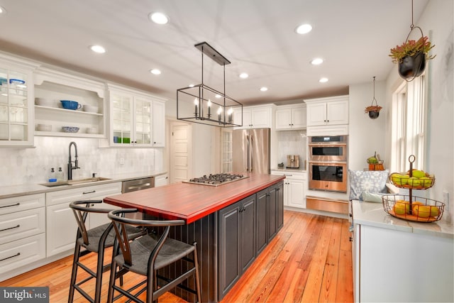 kitchen with white cabinets, backsplash, stainless steel appliances, and a sink