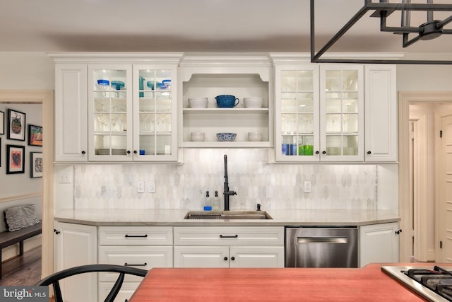 kitchen with a sink, white cabinetry, stainless steel dishwasher, backsplash, and stovetop