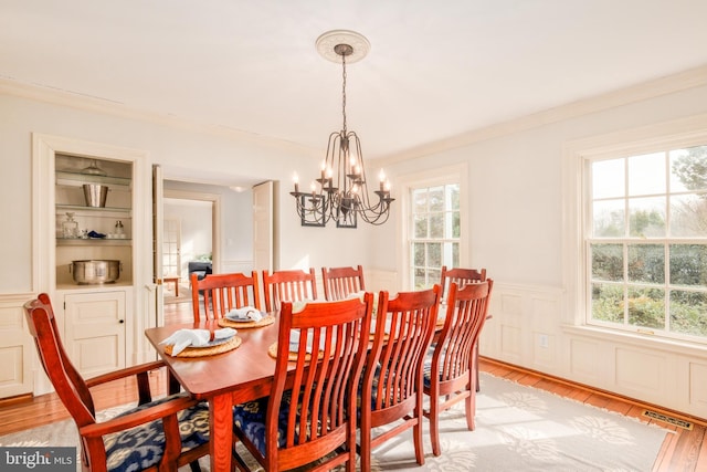 dining space featuring visible vents, built in features, wainscoting, ornamental molding, and light wood-type flooring