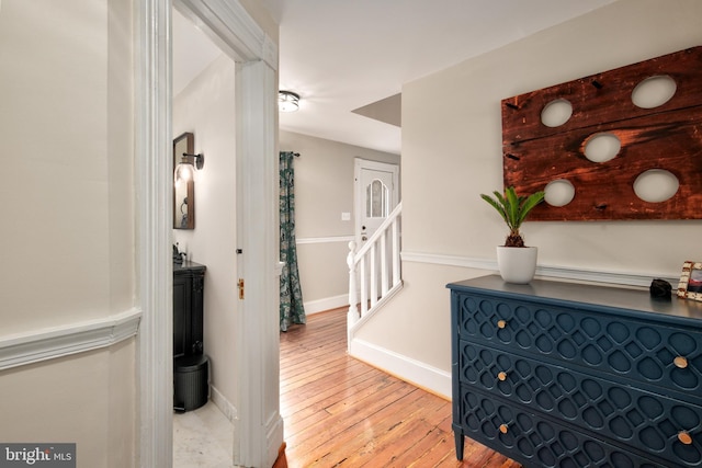 hall featuring wood-type flooring, stairway, and baseboards