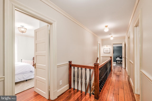 corridor with baseboards, crown molding, light wood finished floors, and an upstairs landing