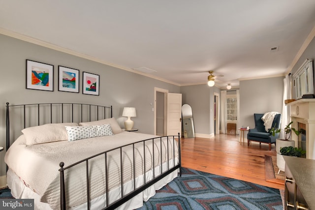 bedroom with visible vents, ornamental molding, ceiling fan, wood finished floors, and baseboards