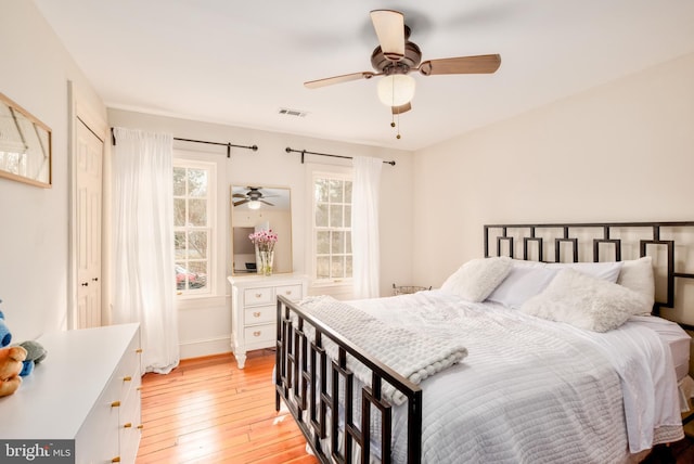 bedroom featuring light wood-style floors, ceiling fan, visible vents, and baseboards