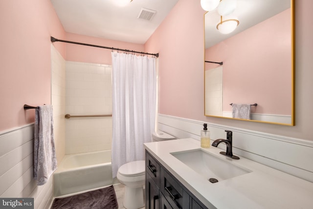 bathroom with a wainscoted wall, toilet, vanity, and visible vents