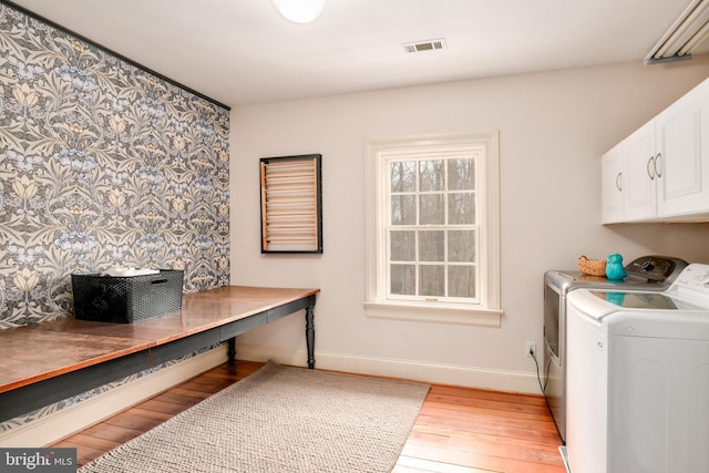 clothes washing area featuring cabinet space, visible vents, separate washer and dryer, light wood-type flooring, and baseboards