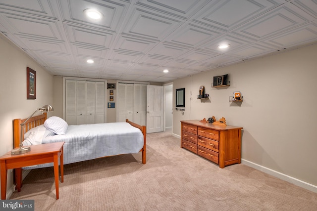 bedroom with light carpet, baseboards, an ornate ceiling, multiple closets, and recessed lighting