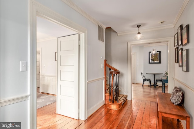 corridor featuring ornamental molding, hardwood / wood-style floors, and visible vents