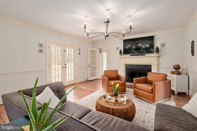 living area featuring ornamental molding, french doors, a fireplace, and wood finished floors