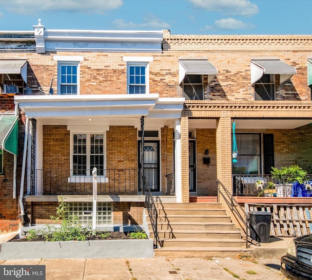 townhome / multi-family property with covered porch and brick siding