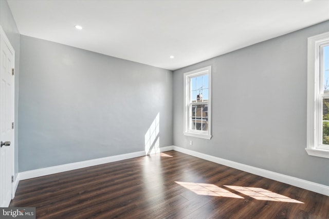 empty room featuring baseboards, dark wood finished floors, and recessed lighting