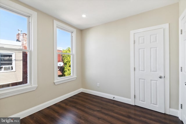 spare room featuring baseboards, dark wood-type flooring, and recessed lighting