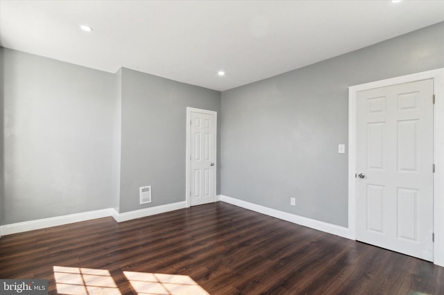 unfurnished room featuring dark wood-style floors, visible vents, and baseboards