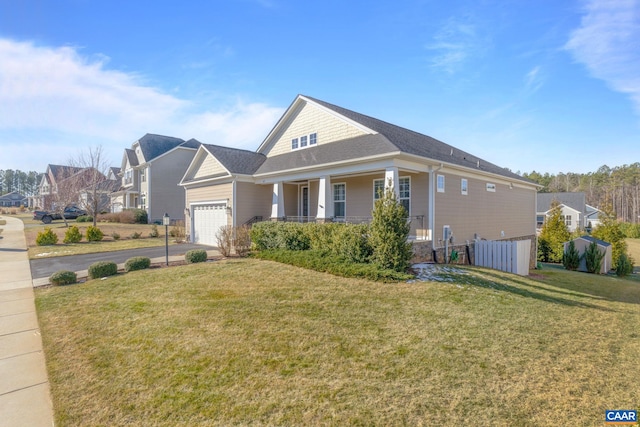 view of front of home featuring a garage, covered porch, driveway, and a front lawn