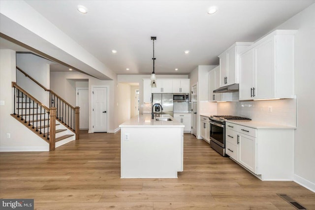 7508 Blue Sun Dr, Glen Burnie, MD 21060 - kitchen with visible vents, appliances with stainless steel finishes, a sink, light wood-type flooring, and under cabinet range hood