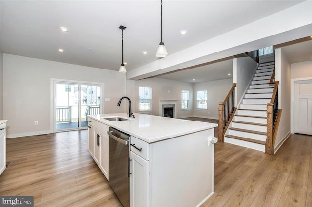 7508 Blue Sun Dr, Glen Burnie, MD 21060 - kitchen featuring stainless steel dishwasher, light wood-style floors, open floor plan, white cabinetry, and a sink
