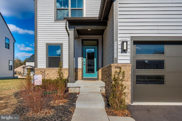 property entrance featuring a garage and brick siding