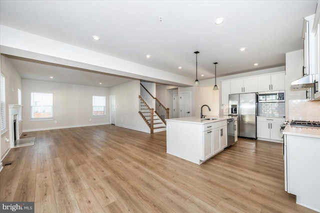 7508 Blue Sun Dr, Glen Burnie, MD 21060 - kitchen with stainless steel appliances, light wood-type flooring, a center island with sink, and decorative backsplash