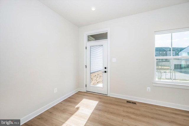 spare room featuring a healthy amount of sunlight, light wood-style floors, baseboards, and visible vents