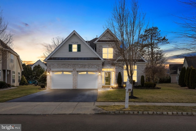 view of front of property featuring a garage, driveway, a yard, and a standing seam roof