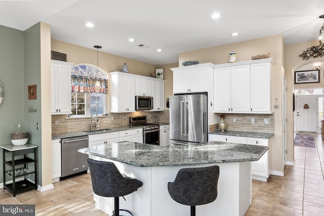 kitchen featuring stainless steel appliances, a center island, a sink, and hanging light fixtures