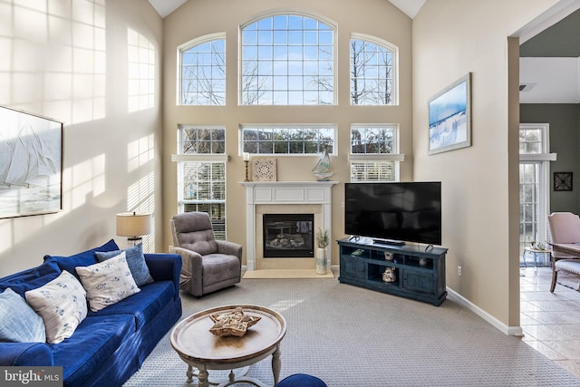 living room with high vaulted ceiling, a fireplace, light colored carpet, and baseboards