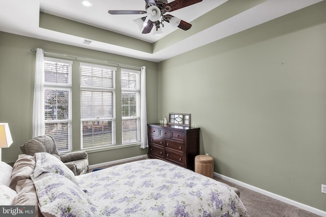 carpeted bedroom featuring visible vents, baseboards, ceiling fan, and a tray ceiling