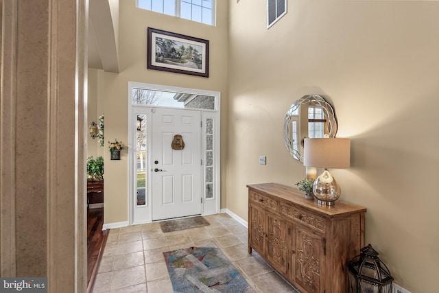 entrance foyer with baseboards, visible vents, and a high ceiling