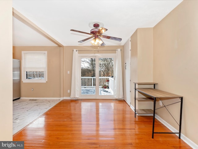 interior space featuring a ceiling fan, baseboards, and wood finished floors